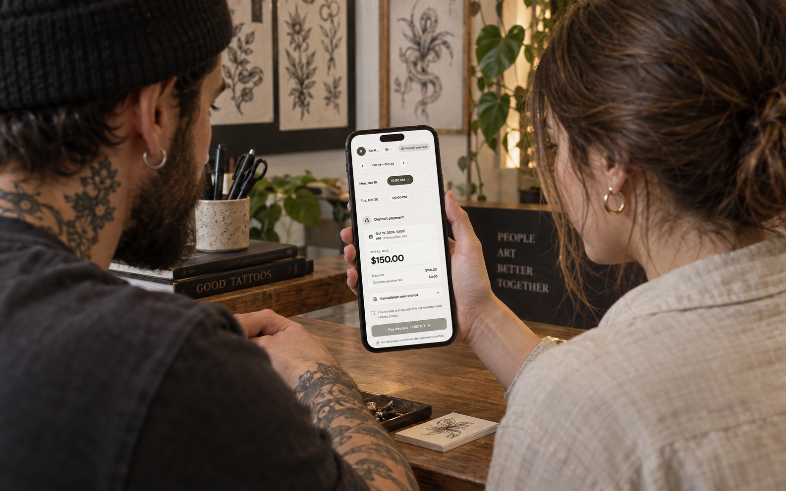 Tattoo artist and client reviewing appointment times and deposit details in English on a phone